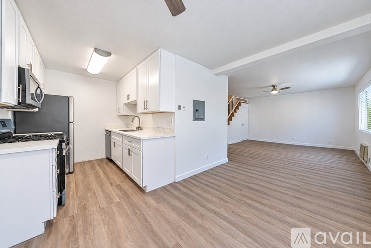 A kitchen with white cabinets and a black fridge.