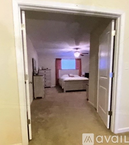 A bedroom with a bed, dresser, and window.