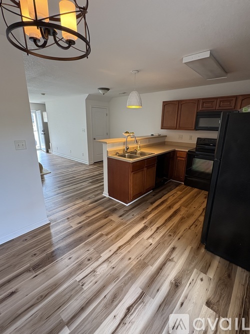A kitchen with wooden floors and a black refrigerator.