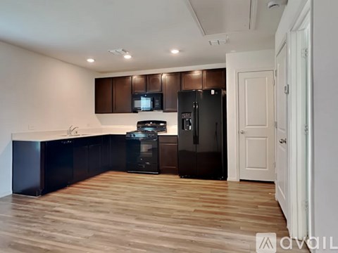 A kitchen with dark brown cabinets and a black fridge.
