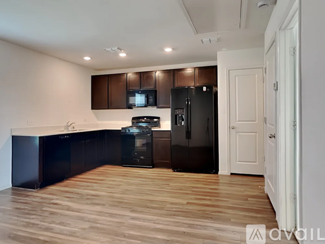 A kitchen with dark brown cabinets and a black fridge.