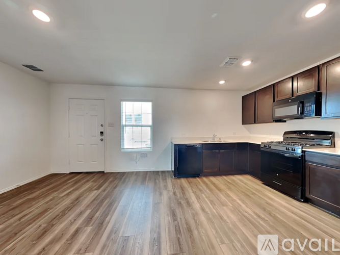 A spacious kitchen with dark wood cabinets and a white door.