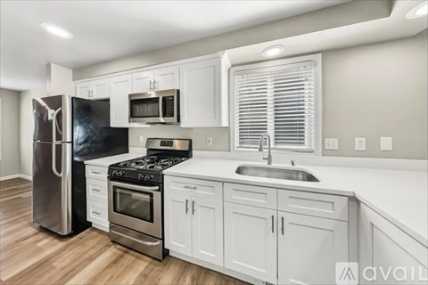 A modern kitchen with white cabinets and stainless steel appliances.