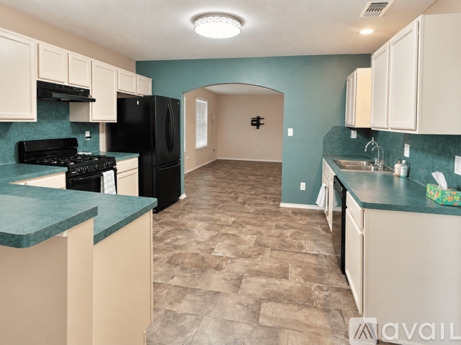 A kitchen with a black refrigerator and a green counter top.
