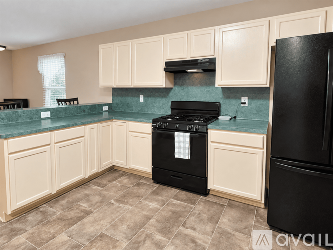 A kitchen with black appliances and white cabinets.