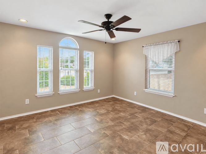 A room with a ceiling fan and three windows.