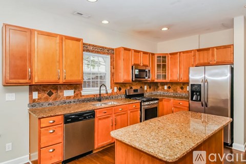 A kitchen with orange cabinets and granite countertops.