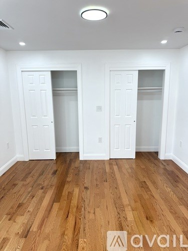 A room with wooden floors and white walls, with two doors and a logo that reads "avail".