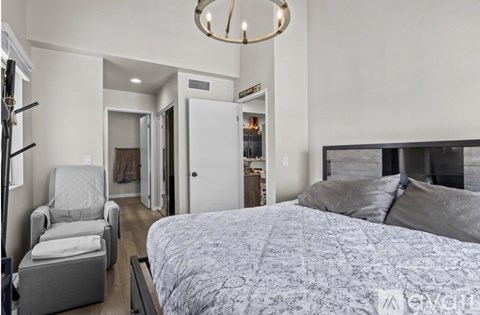 A bedroom with a large bed and a chair.