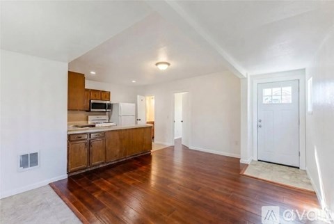 A spacious room with wooden floors and white walls.