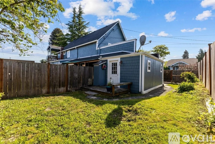 A blue house with a white door and a window is surrounded by a wooden fence.