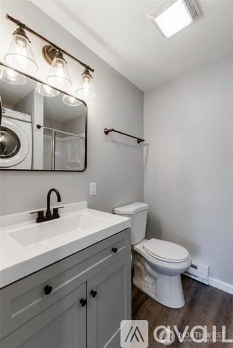 A bathroom with a white toilet, a sink with a black faucet, and a mirror above the sink.