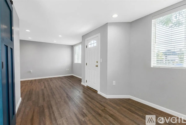 A spacious room with wooden flooring and white walls.