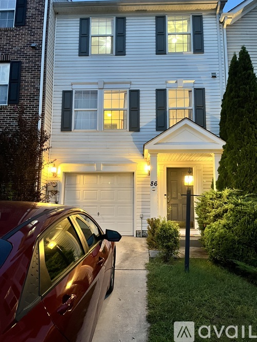 A red car is parked in front of a house with the number 86 on the front door.