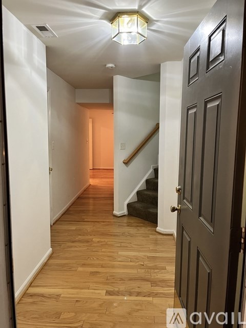 A hallway with a wooden floor and a staircase.