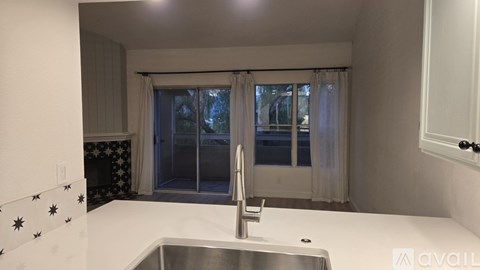 A kitchen with a sink and a window with curtains.