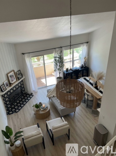 A living room with a wooden floor and a large window with white curtains.