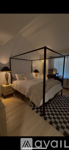A bedroom with a four-poster bed and a black and white checkered rug.