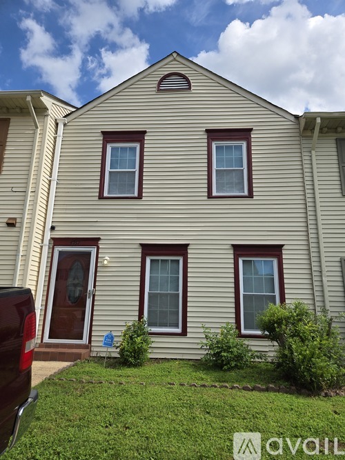 A house with a brown door and windows with a sign in front of it.