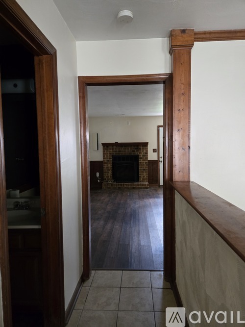 A hallway with a fireplace and a doorway leading to another room.