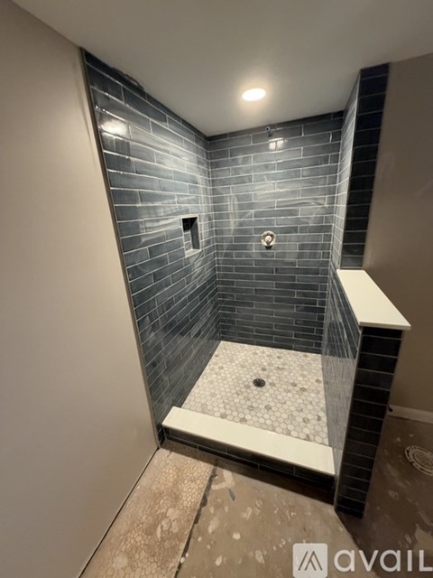 A bathroom with a shower area featuring a tiled wall and floor.