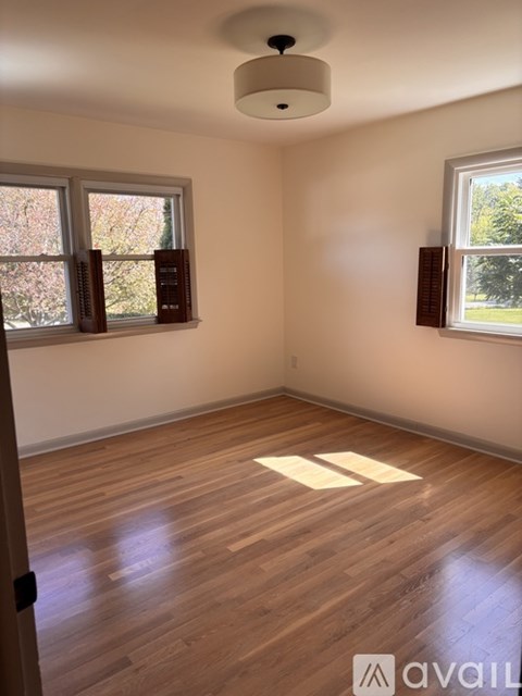 A room with wooden floors and two windows.