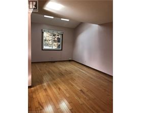 A room with wooden flooring and a window showing trees outside.