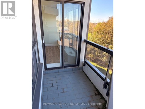 A balcony with a glass door and a view of trees.