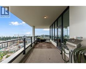A balcony with a grill and a view of a parking lot and buildings.