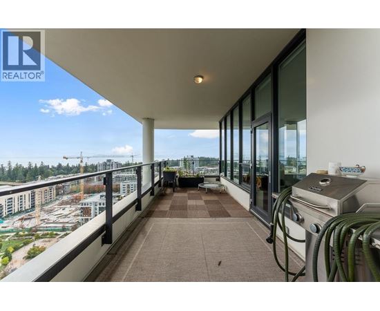 A balcony with a grill and a view of a parking lot and buildings.