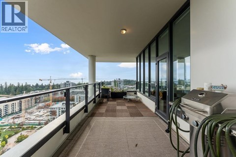 A balcony with a grill and a view of a parking lot and buildings.
