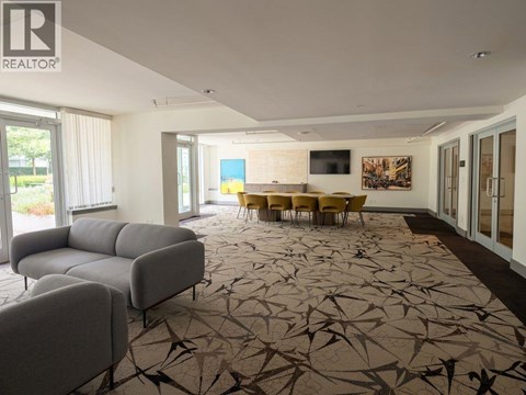 A living room with a grey sofa and a patterned carpet.