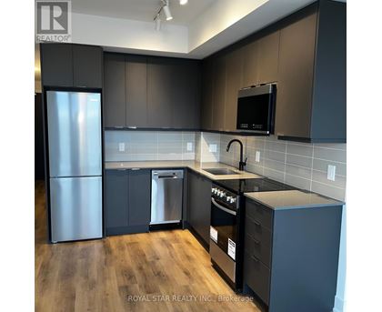 A kitchen with dark brown cabinets and a black microwave.