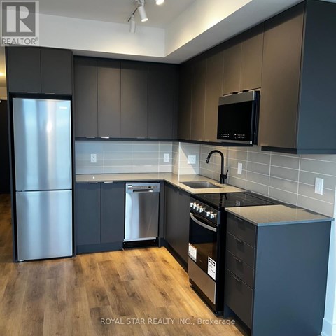 A kitchen with dark brown cabinets and a black microwave.