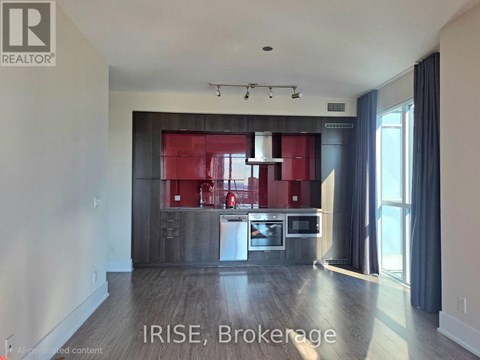 A modern kitchen with a red backsplash and stainless steel appliances.