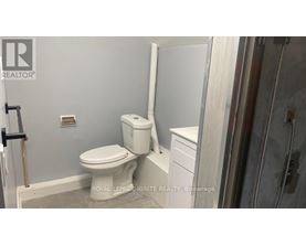 A white toilet in a bathroom with a white cabinet and a white towel rack.