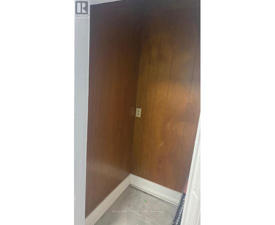 A room with a wooden wall and a white baseboard.