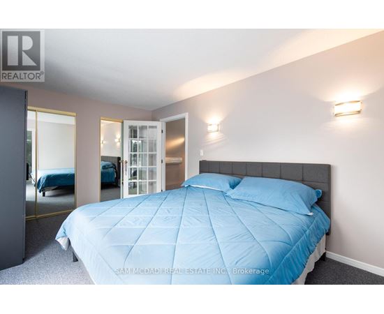 A bedroom with a bed covered in a blue comforter.