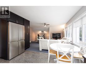 A kitchen with a refrigerator, a table and chairs, and a television.