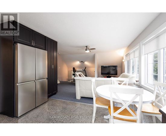 A kitchen with a refrigerator, a table and chairs, and a television.