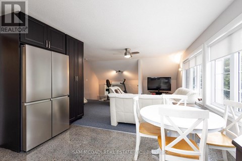 A kitchen with a refrigerator, a table and chairs, and a television.