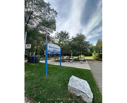 A sign for Manor Community Green is displayed in front of a grassy area.