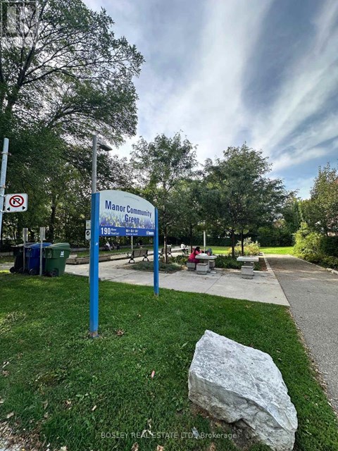 A sign for Manor Community Green is displayed in front of a grassy area.
