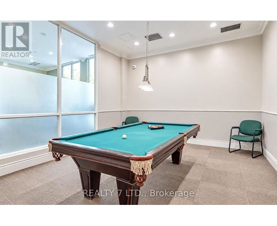 A pool table in a room with a chair and a window.