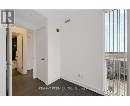 A white hallway with a door on the left and a balcony on the right.