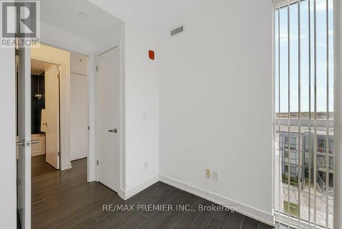 A white hallway with a door on the left and a balcony on the right.