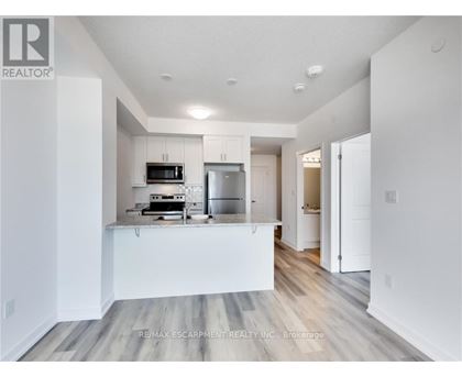 A modern kitchen with white cabinets and a wooden floor.