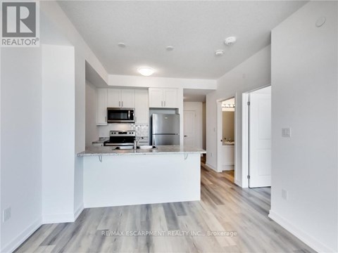 A modern kitchen with white cabinets and a wooden floor.