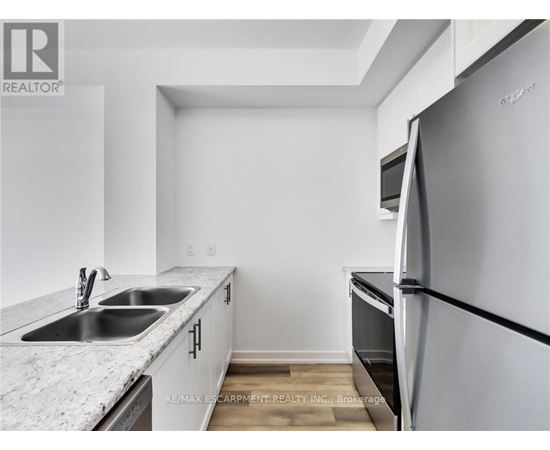 A kitchen with a refrigerator, sink, and countertop.