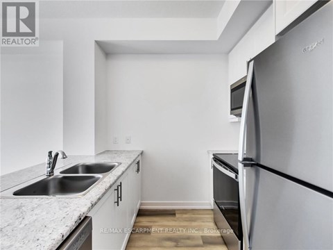 A kitchen with a refrigerator, sink, and countertop.